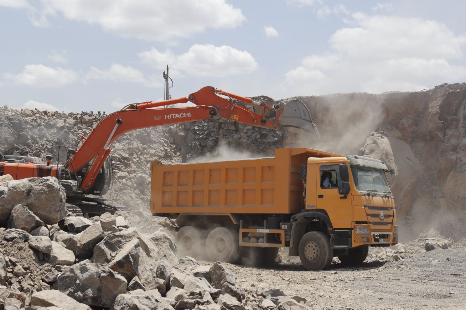 Excavator loading a tipper truck with quarried rock