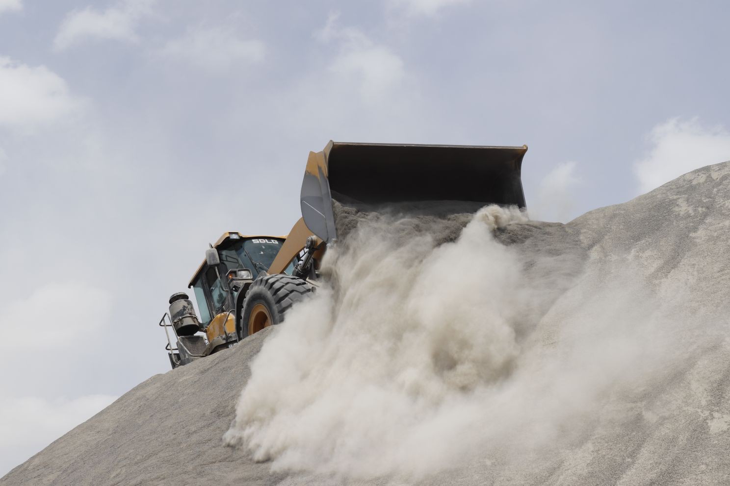 Wheel loader releasing dust over a stockpile